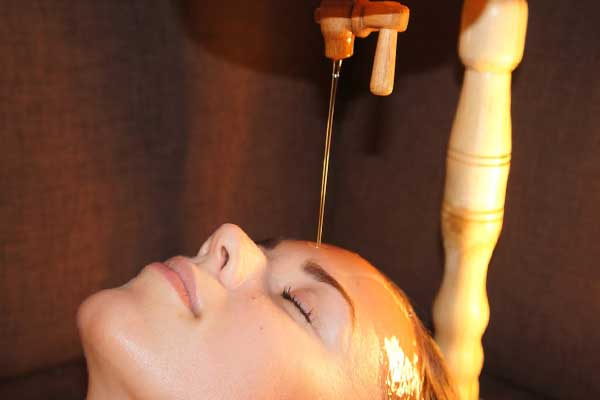 растительное масло льётся на лоб, аюрведа