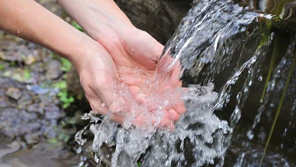 девушка набирает родниковую воду в руки